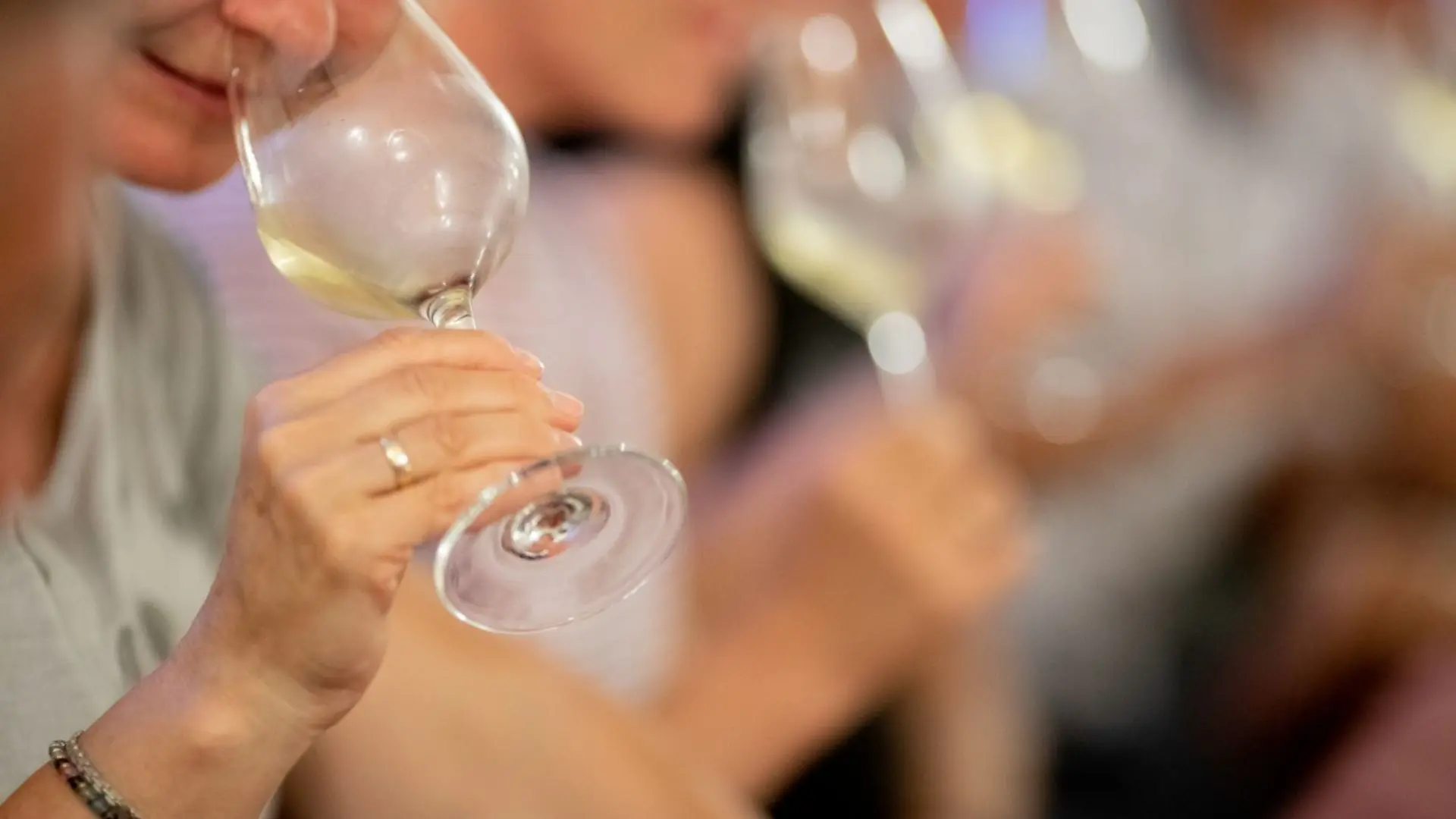 A wine tasting experience at the Baglio Ingardia winery. A person can be seen drinking white wine out of glass. There are more people in the background, also drinking white wine.