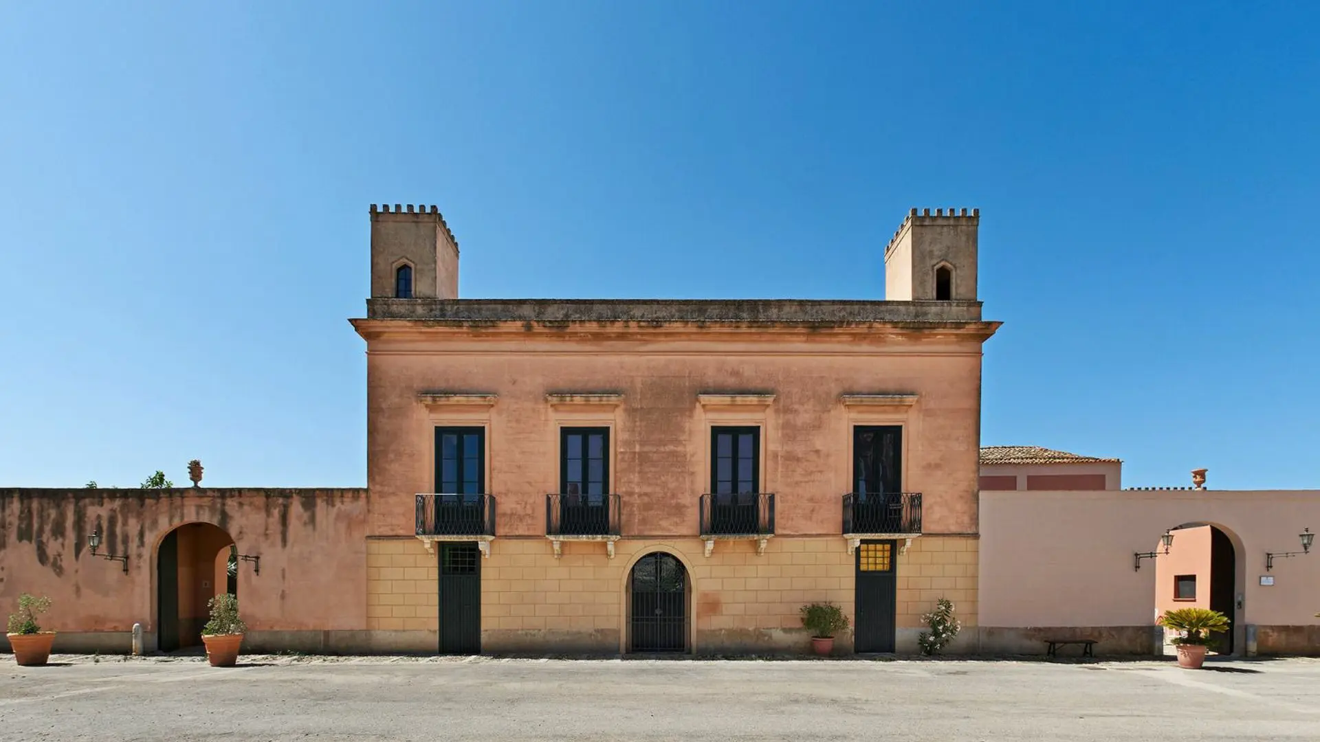 The 18th century building of the Baglio Ingardia winery in Sicily, Italy. Behind the old, stone building, you can see a blue skyline.