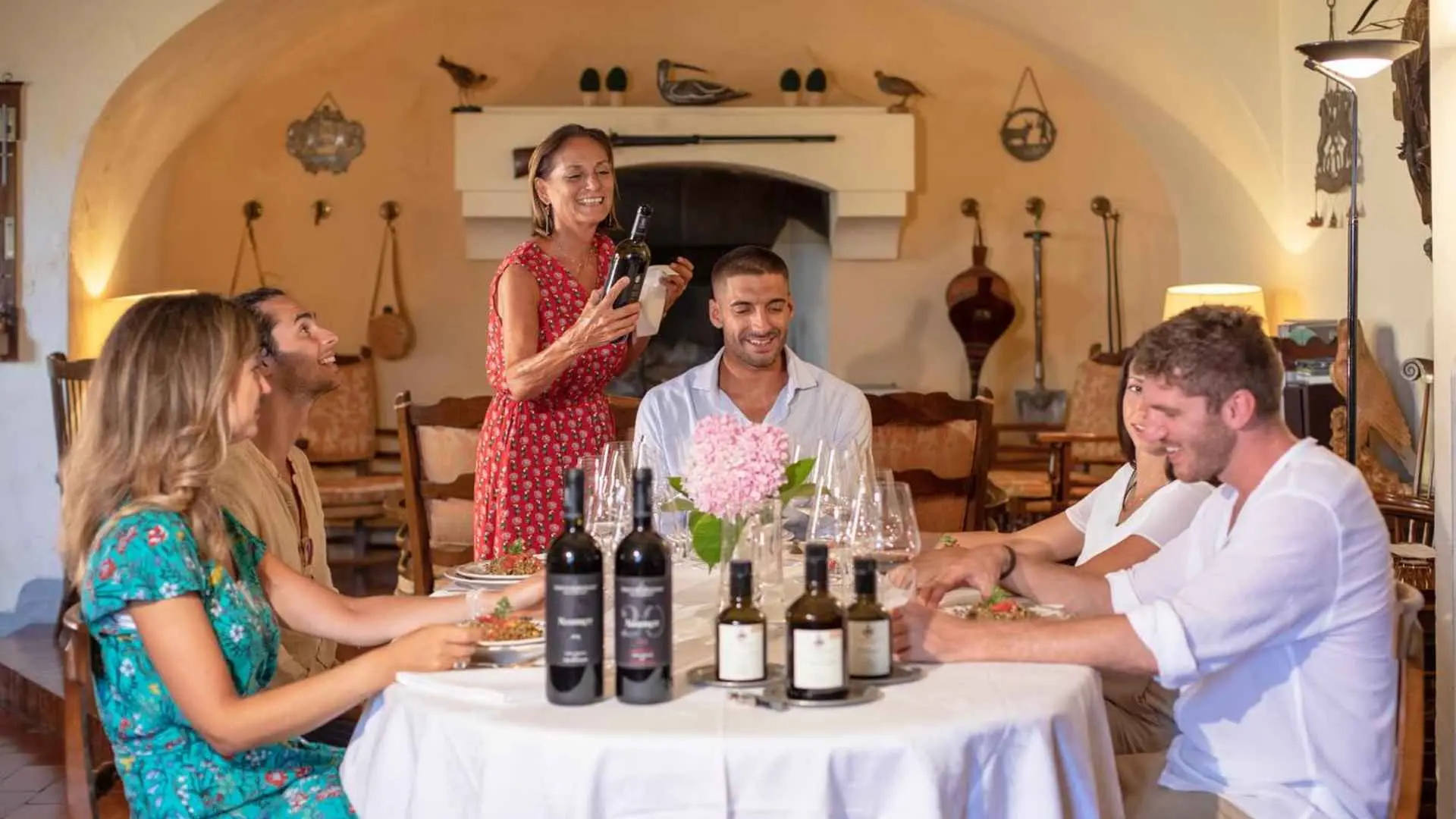 Tenuta di Ghizzano wine tasting experience. Five people are seated at a table, with bottles of wine, glasses, and food.