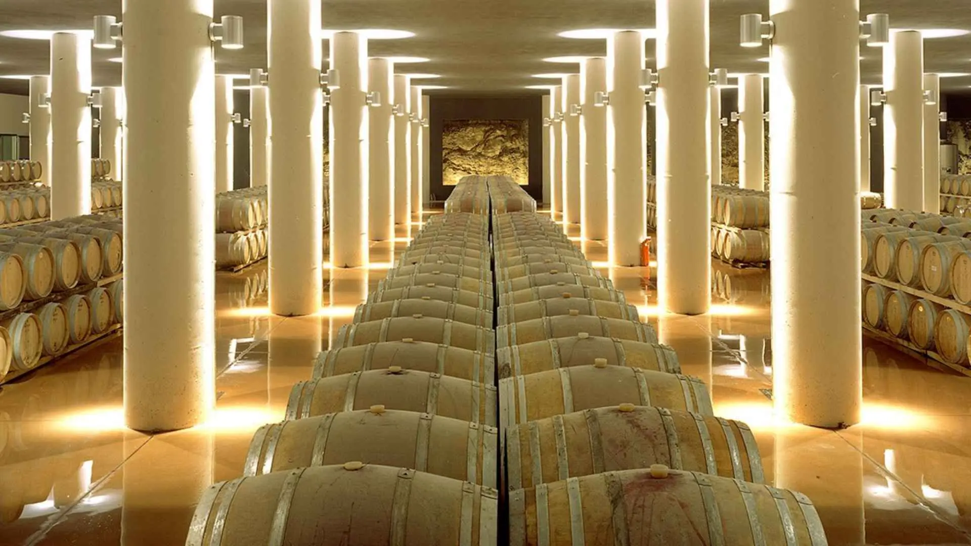 The image shows a very well lit wine cellar and stacked rows of barrels at the Castello di Fonterutoli winery.