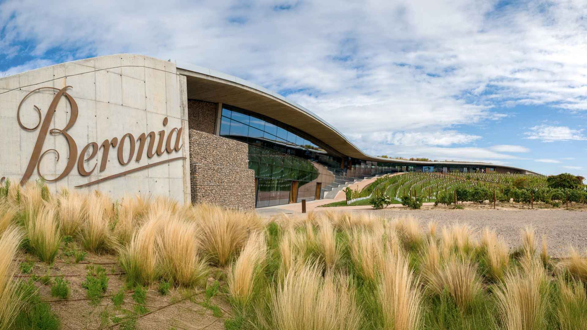 The image shows grass, vineyards and a part of the Beronia winery building.