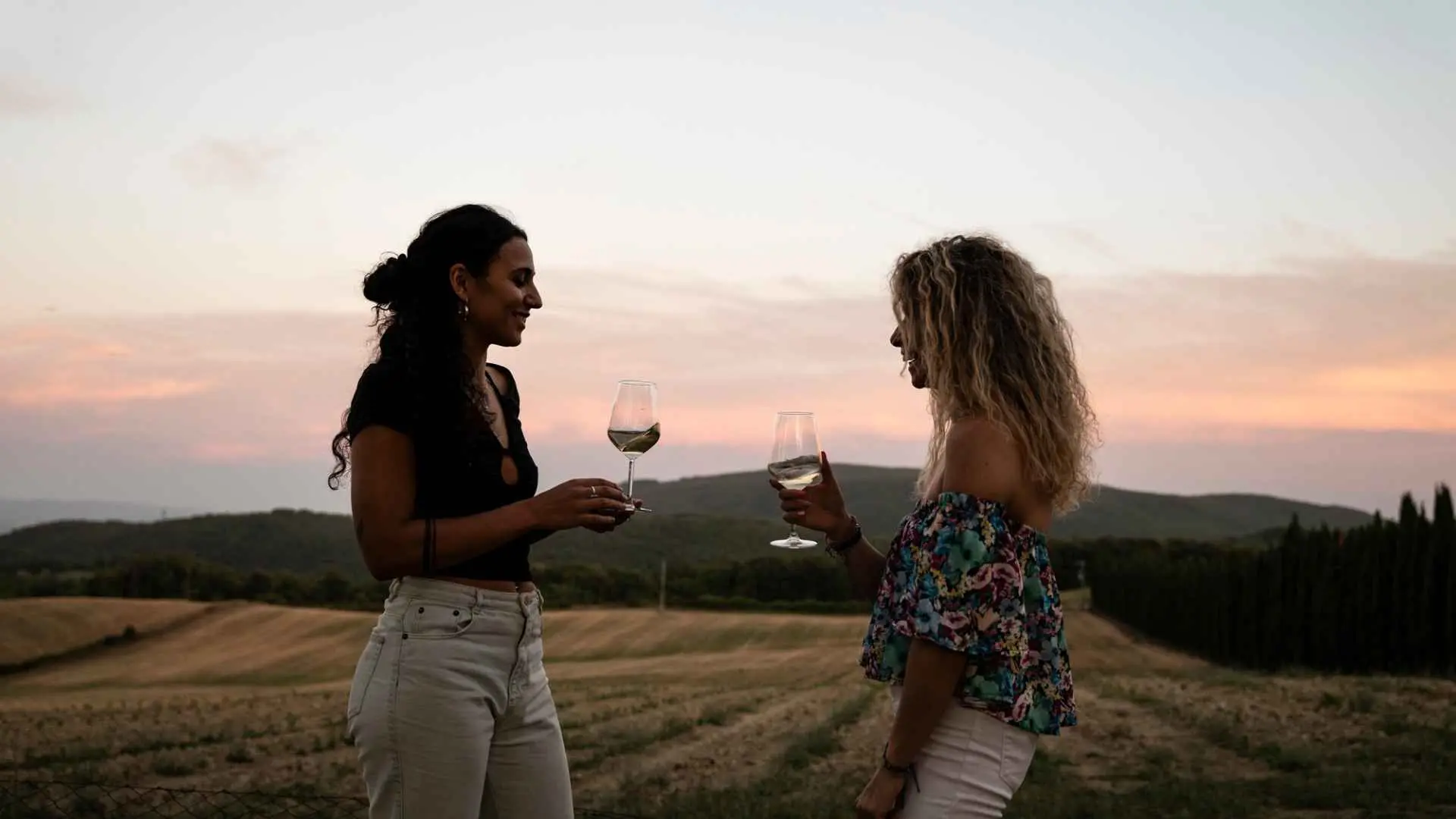 The image shows two women drinking wine at the Fattoria La Torre winery, right after a sunset. 