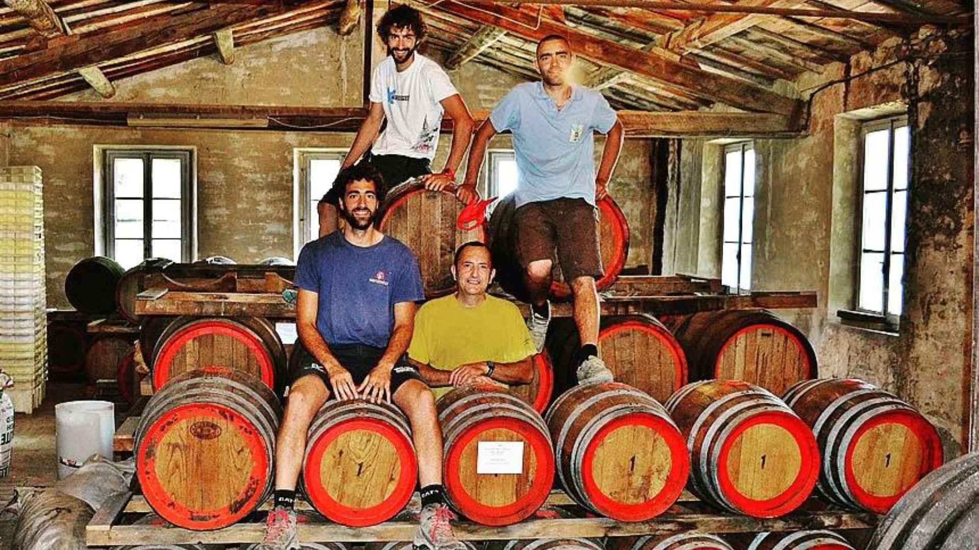 There are four men on top and behind a plethora of wine barrels inside the FAttoria Di Montemorli winery.