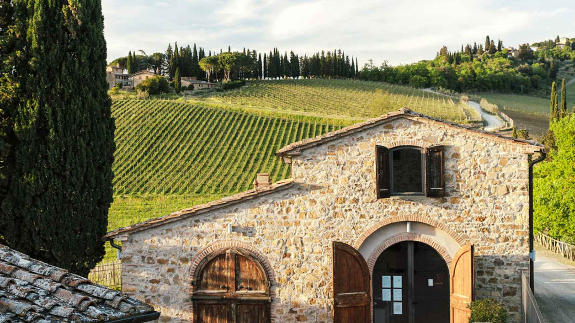 You can see the old stone buildings of the Caffagio winery, as well as the vineyard in the background, as well as an overcast sky.