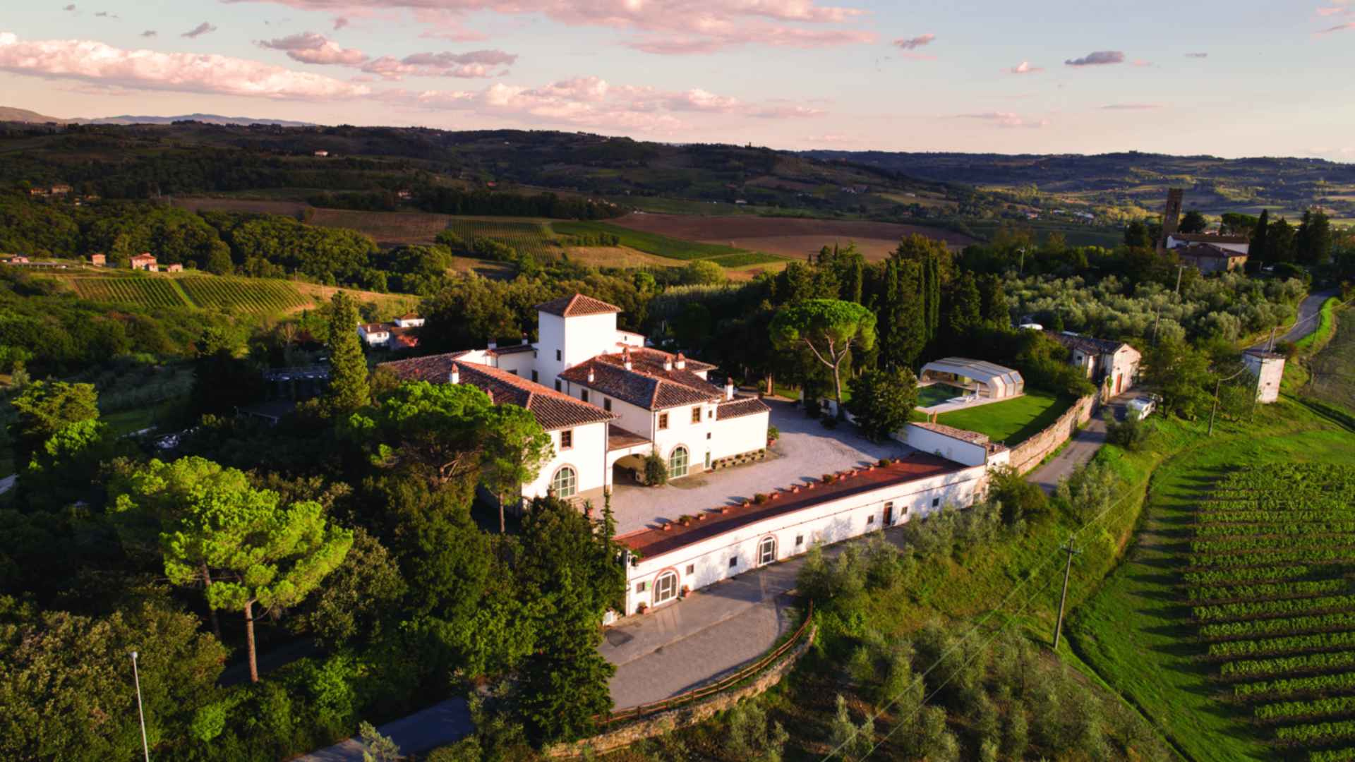 The photo shows the winery and vineyard of Fattoria San Mcihele a Torri. The photo was taken during a colorful sunset.