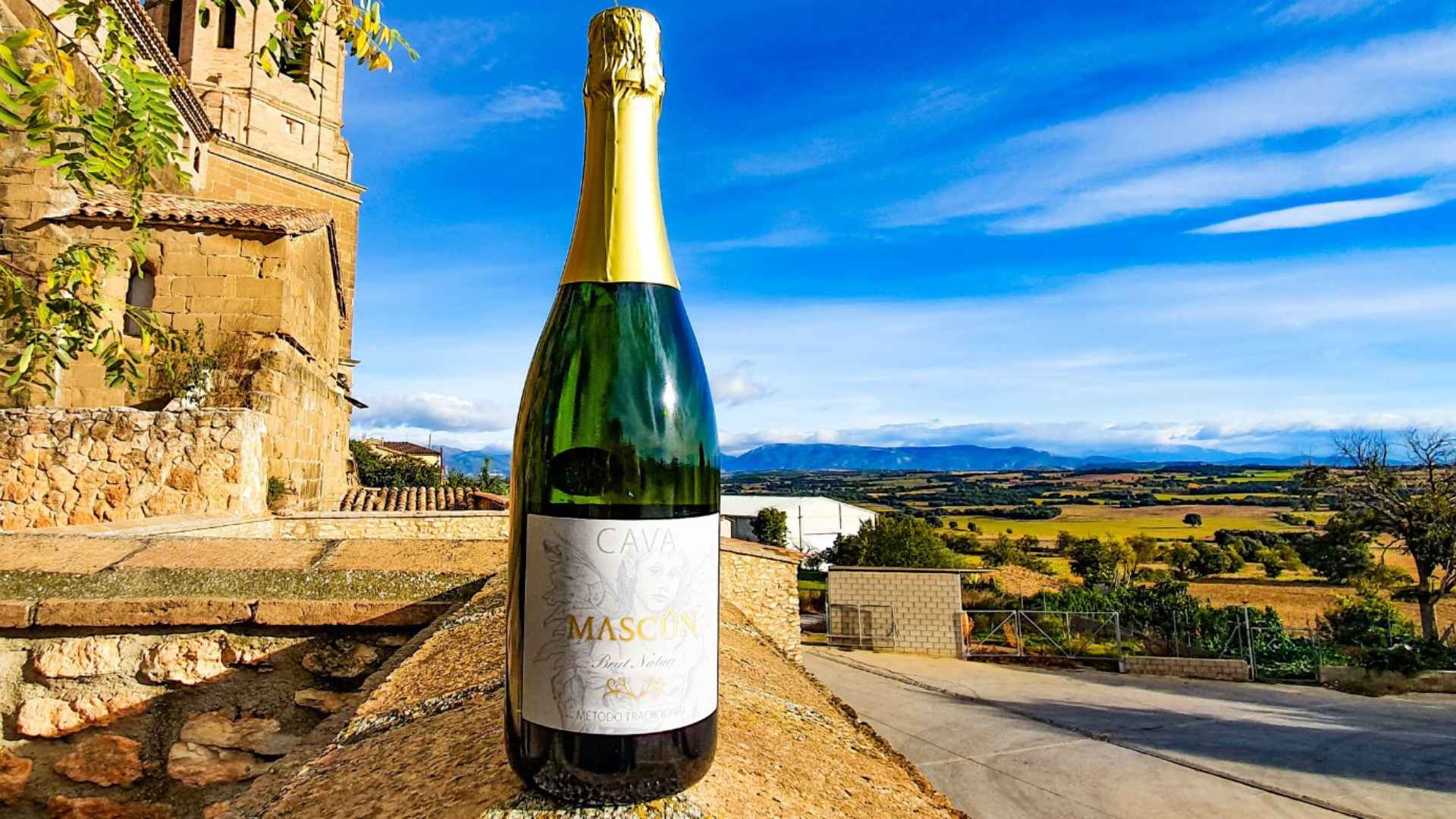 A bottle of wine on the balcony of the Bodegas Osca winery. The sky is blue but overcast and the time of day is the afternoon.