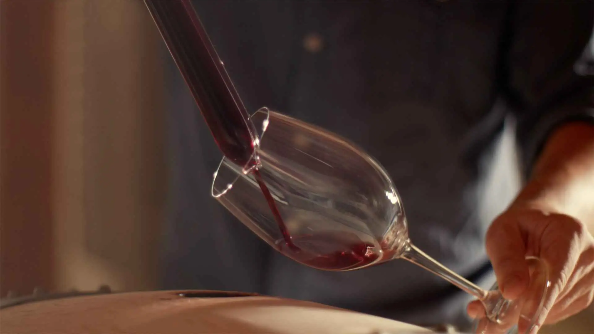 A person filling a glass of wine with red wine, using a specialized tool, at the Bodega Torralbenc.