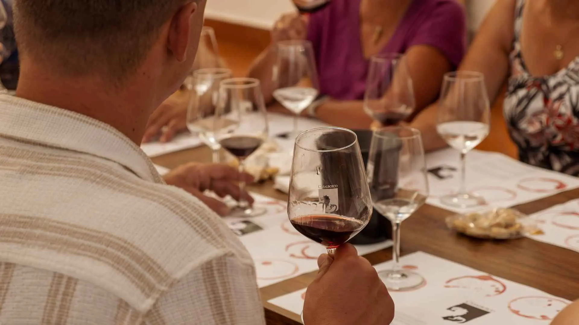 Fattoria Casalbosco wine tasting experience. There are people seated at a table and they are drinking all sorts of wine, while also having food.