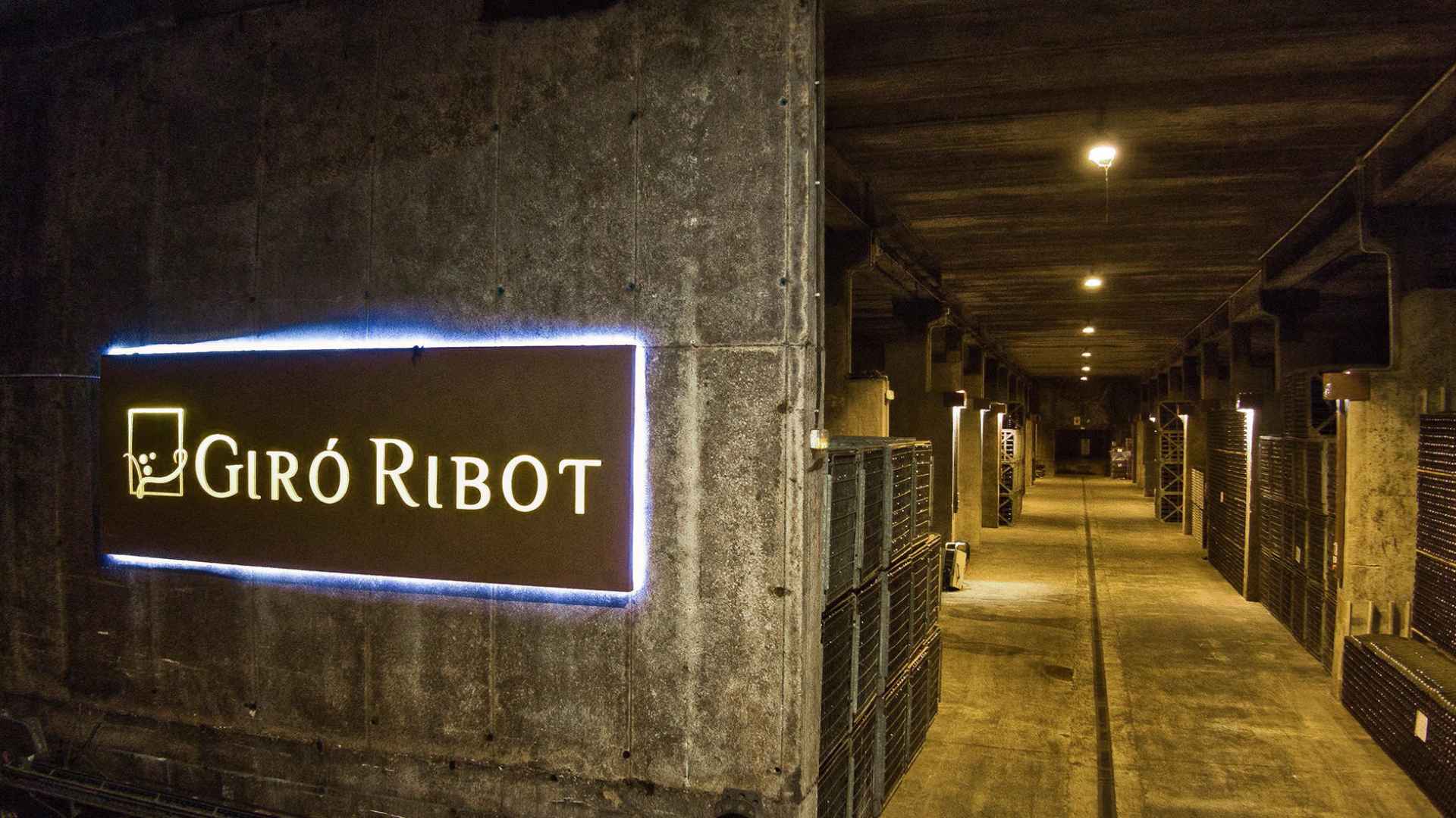 The Giro Ribot winery cellar. Crates of wine bottles can be seen in the back, while the winery's name is on a sign on the left part of the image.