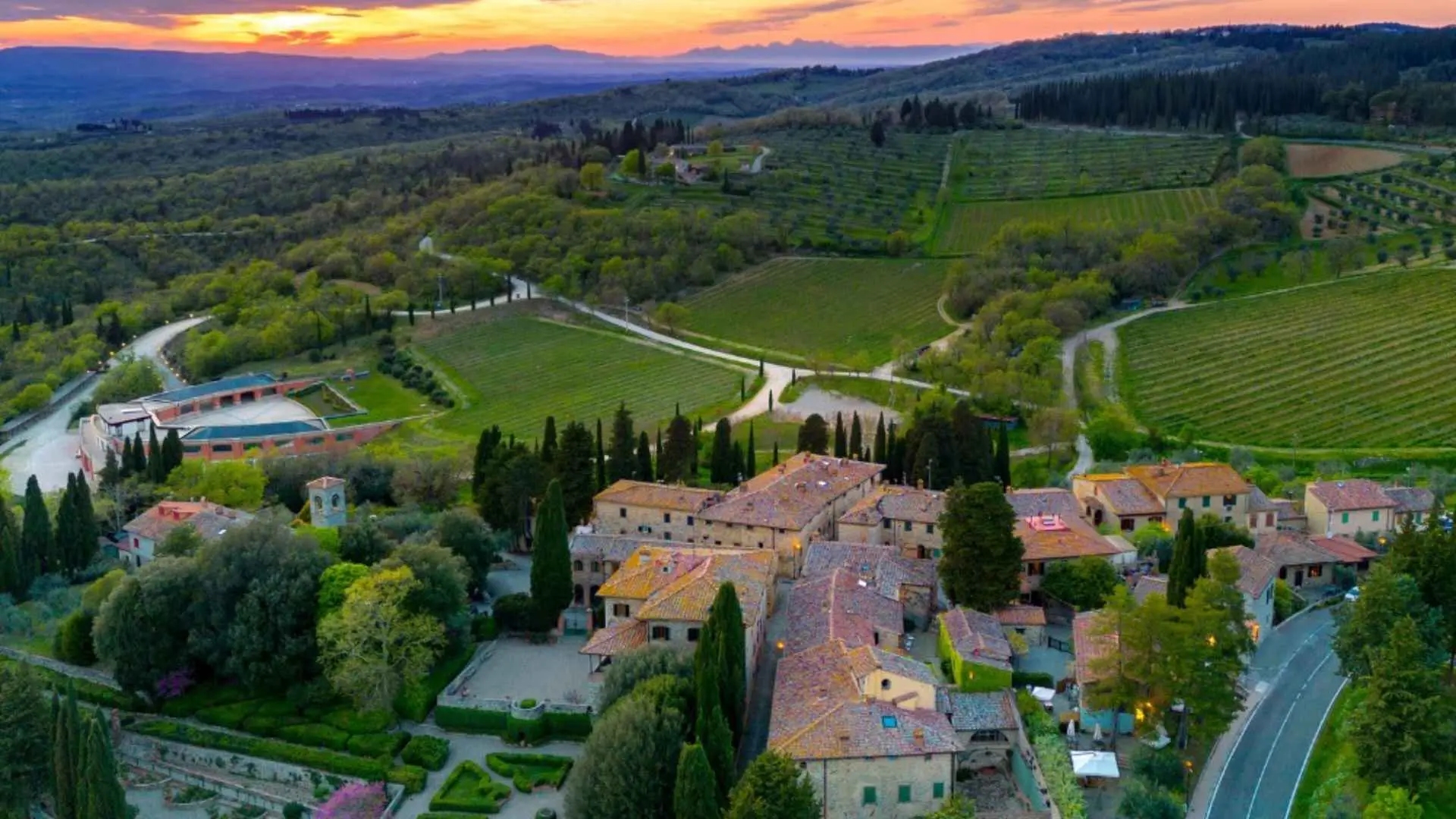 The image shows the Castello di Fonterutoli winery and vineyards during a sunset. It is taken from above so you can see the entire surroundings.