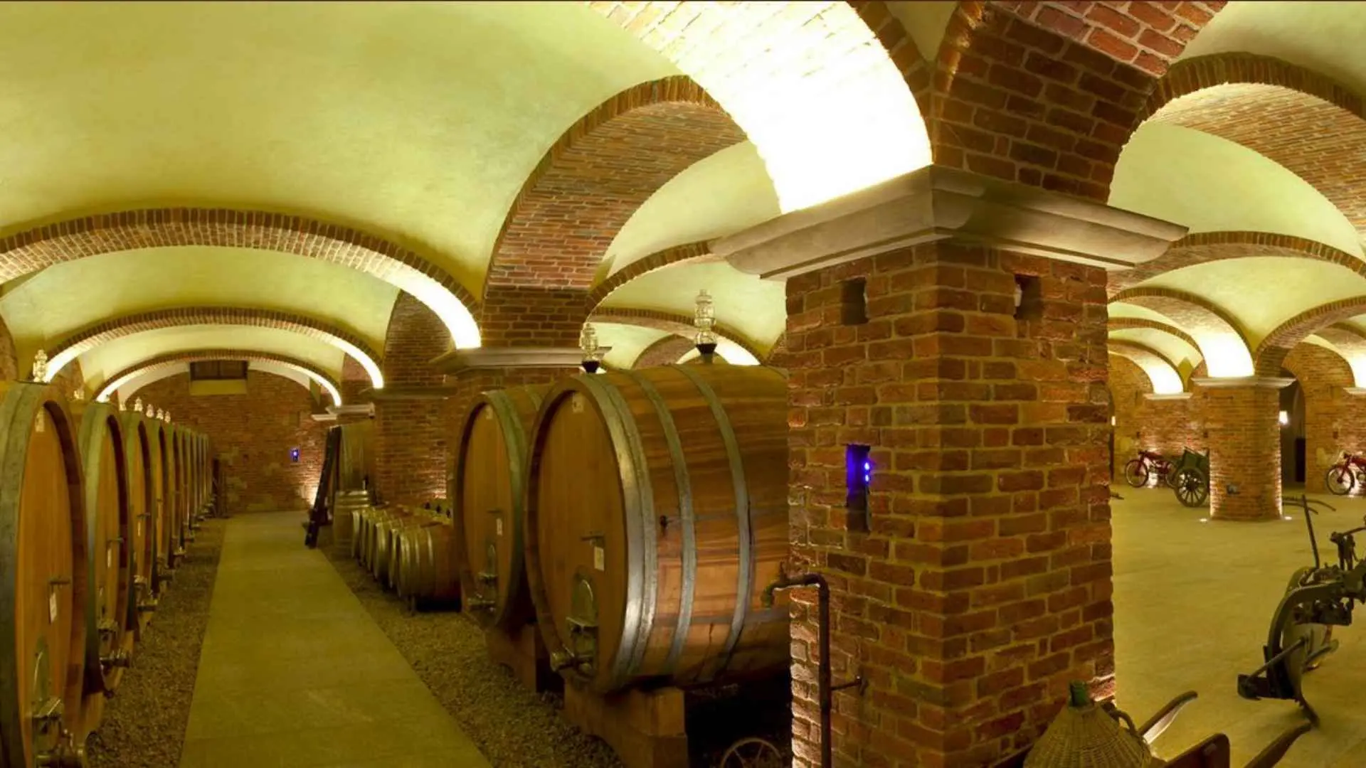 The wine cellar of the Cantine Povero winery. It has brick pillars and a typical layout of huge wine barrels stacked one next to another.