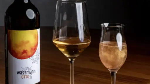 A bottle of Wassmann Otto wine, and two different glasses, both filled with the same wine.